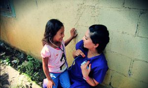 A volunteer shares her heartbeat via a stethoscope with a child.